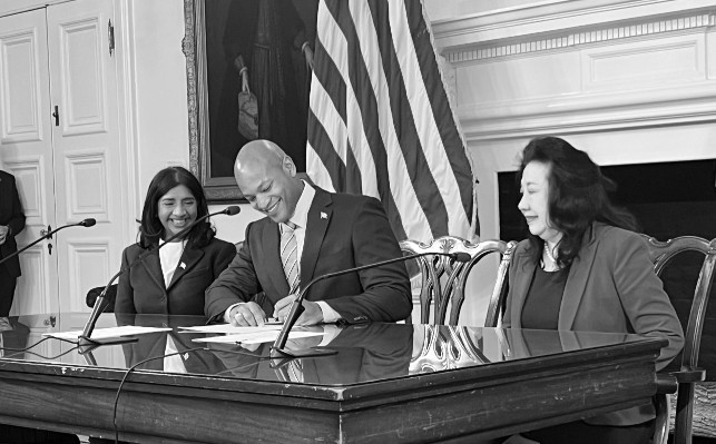 Photo courtesy: Michael Charles/Capital News Service. Gov. Wes Moore signs executive orders releasing abortion training and other funds in his first full day in office. Lt. Gov. Aruna Miller and Secretary of State Susan Lee look on. 