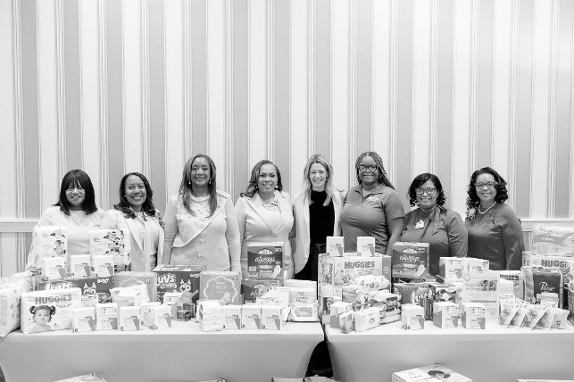 Photo Credit: Mid-Atlantic and North Atlantic Regions Leaders and members of Alpha Kappa Alpha Sorority, Incorporated ® showcase baby and menstrual products AKA members donated to the Greater DC Diaper Bank at the sorority’s 118th Founders’ Day Celebration in National Harbor, MD, January 3, 2026. More than 13,000 items valued at $29,000 were donated. From left: Tracy Terrell; Melody Johnson Morales; Alpha Kappa Alpha North Atlantic Regional Director Elicia Pegues Spearman, Esq.; Alpha Kappa Alpha Mid-Atlantic Regional Director Nadine Vargas Stewart; Greater DC Diaper Bank Executive Director Liz Schurgin; Ashley Jones, Greater DC Diaper Bank; Jacqueline Jiles; Antionette Duncombe